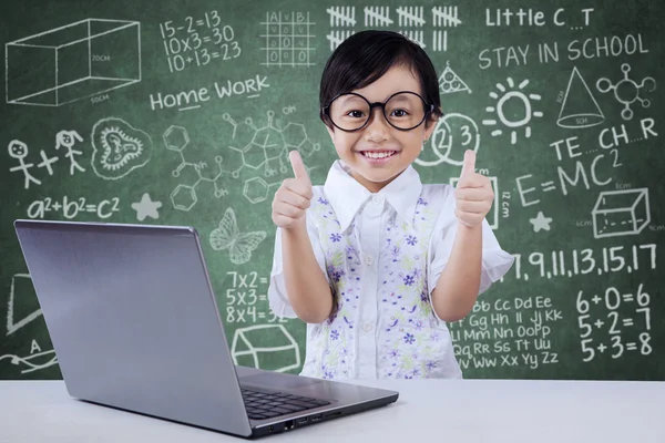 Child with laptop shows OK gesture in class — Stockfoto
