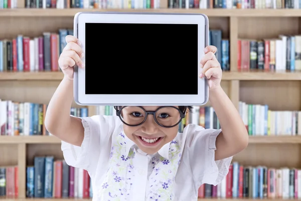 Belle enfant montrant tablette dans la bibliothèque — Photo