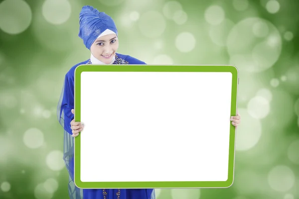 Pretty muslim woman holds empty board — Stockfoto
