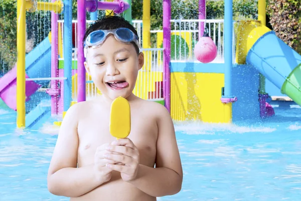 Criança pequena comendo sorvete na piscina — Fotografia de Stock