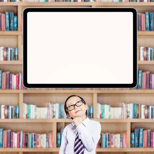 Schoolboy imaginar algo na biblioteca — Fotografia de Stock