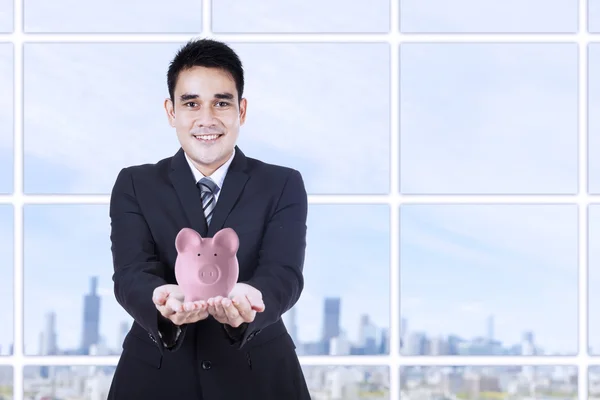 Un hombre de negocios sonriente sosteniendo una alcancía —  Fotos de Stock