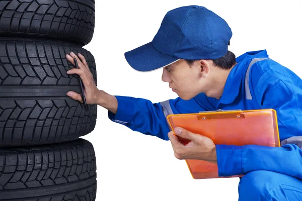 Técnico com uniforme azul verifica pneus — Fotografia de Stock