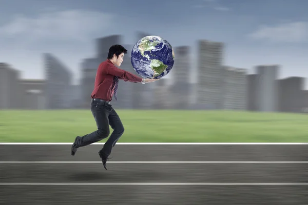 Young businessman running with globe — ストック写真