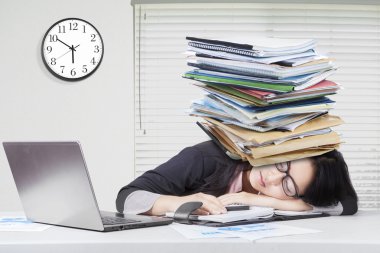 Woman sleeping in office with paperwork on head