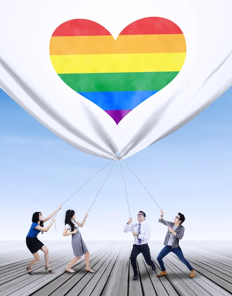 People pulling banner with colorful heart — 图库照片