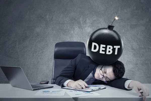 Stressful businessman sleeping on desk with bomb — Stockfoto