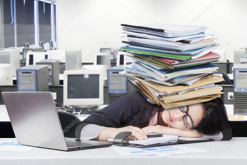 Depressed female worker napping on desk