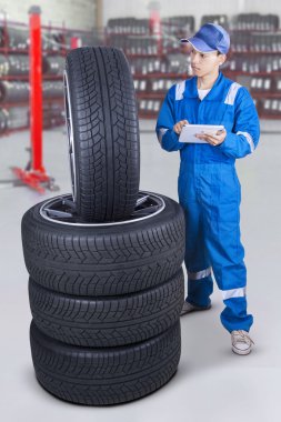 Male mechanic using a tablet to check tires
