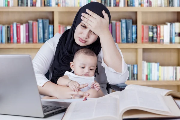 Wanita tertekan bekerja dengan bayi di perpustakaan — Stok Foto