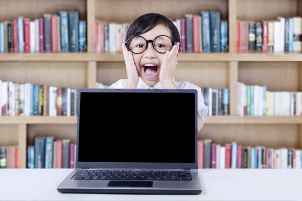 Expressive child with laptop screaming in library — Φωτογραφία Αρχείου