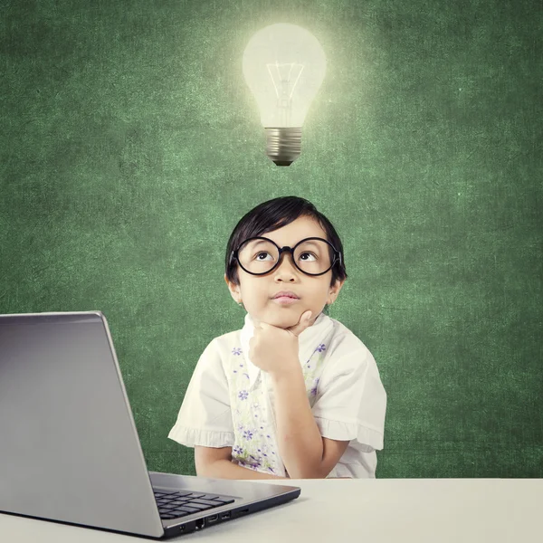 Niño genio con portátil piensa idea bajo la lámpara —  Fotos de Stock