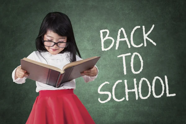 Menina de volta à escola e ler um livro — Fotografia de Stock