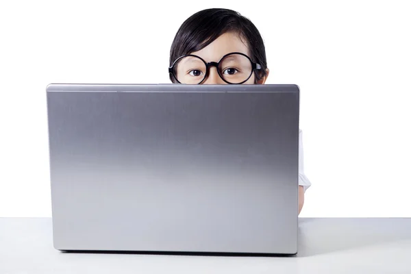 Menina espreitando da parte de trás do laptop — Fotografia de Stock