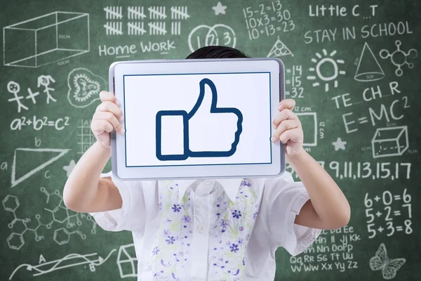 Little student showing a thumb up symbol on tablet — Stock Photo, Image