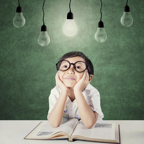 Lovely child with book looking up at lamp — Stockfoto