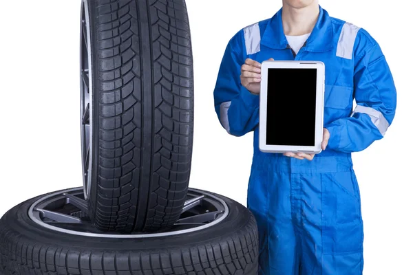 Mechanic showing tablet screen near tires — Stok fotoğraf