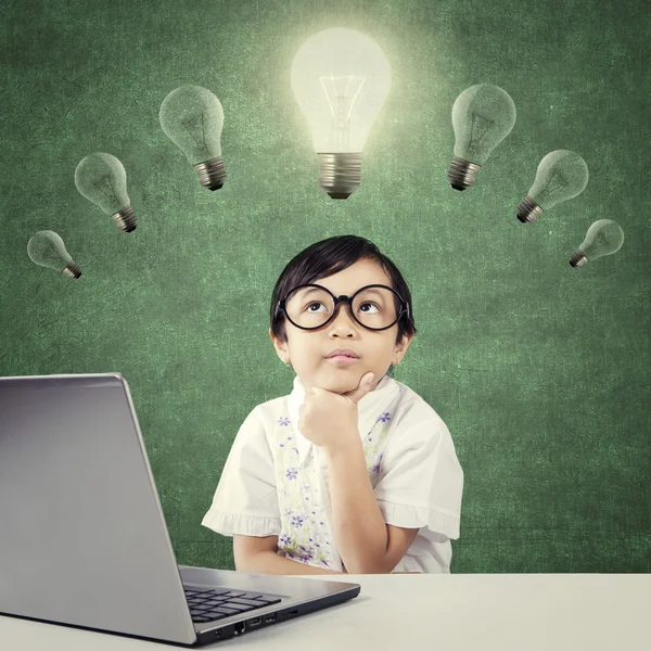 Pensive kid sitting under lamp with laptop — 图库照片