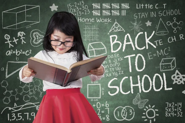 Preschool girl reads book seriously — Stok fotoğraf