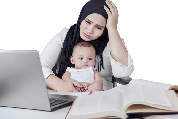 Stressful young housewife working with her baby — Stockfoto