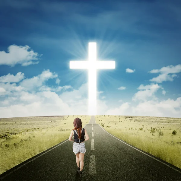 Teenage girl on the road with a cross — Stok fotoğraf