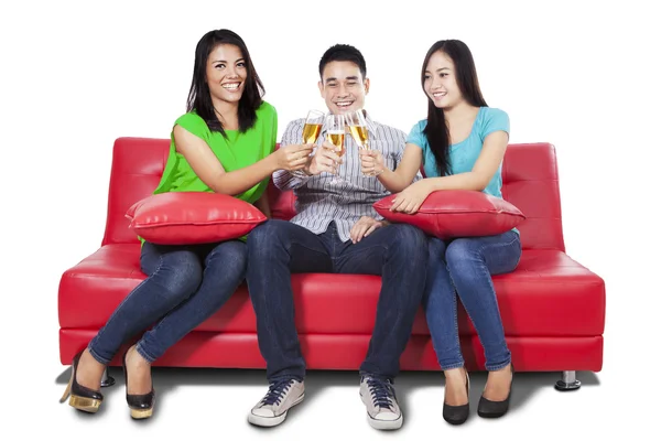 Teenagers drinking champagne on sofa — Stock fotografie