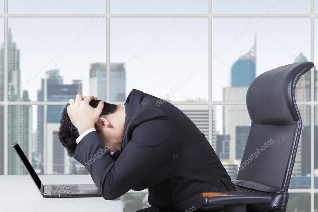 Hopeless worker working with laptop in office