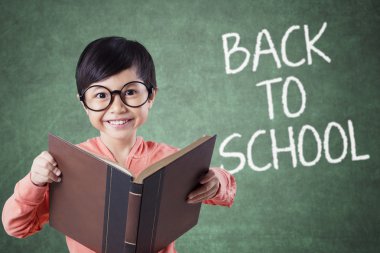 Child holds book with back to school text in class
