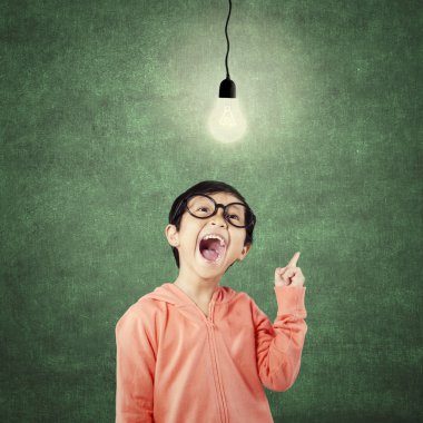 Clever kindergarten student pointing at bright lamp