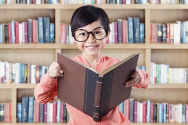 Girl standing in library while reading textbook