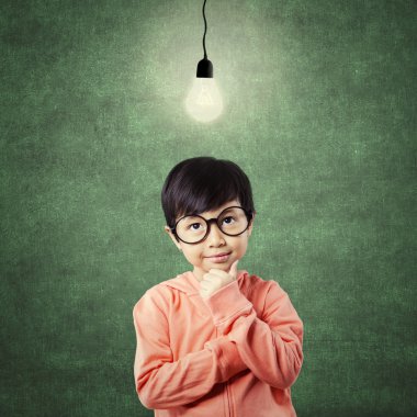 Kid in thinking poses while looking at light bulb