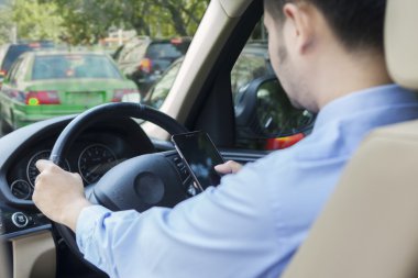 Man driving his car while texting with cellphone clipart