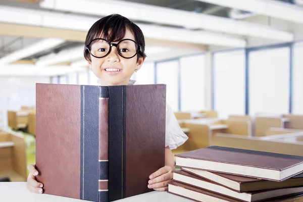 Attractive schoolgirl reading textbooks in class — Stok fotoğraf
