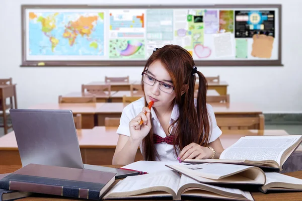 Brunette student studying on desk in class — Stockfoto