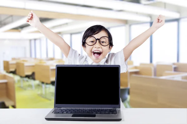 Happy kid with laptop raise hands in class — Stock Photo, Image