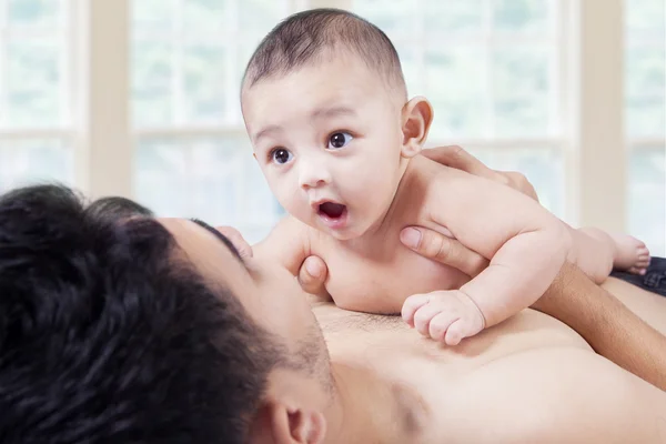 Bayi bermain di dada ayah di rumah. — Stok Foto