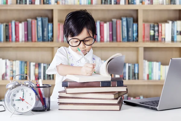 Lovely female student writing in the library — 图库照片