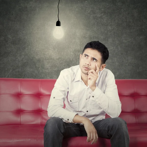 Man thinking idea on sofa while look at lamp — Stock fotografie