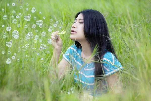 Pretty woman blowing bubble on the meadow — Stockfoto