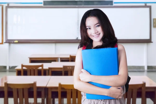 Девочка-подросток держит папку в классе — стоковое фото