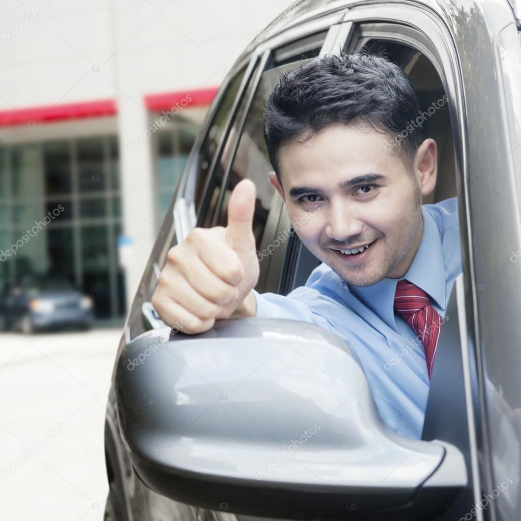 Young man shows thumb up in the car