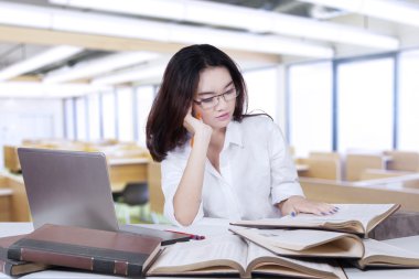 Female student with long hair reading books in class