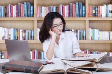 Student sitting in library while reading books