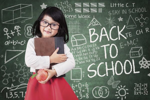 Kindergarten student holds book and apple