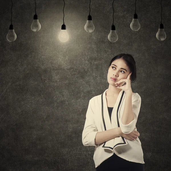 Pretty woman thinking under lightbulb — Stock Photo, Image