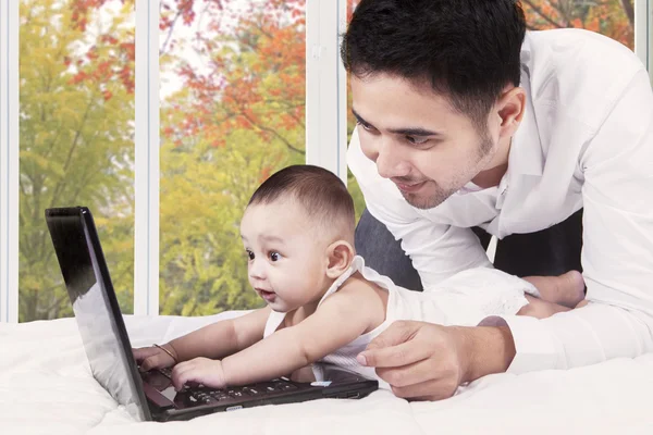 Любопытный ребенок с папой играет на ноутбуке — стоковое фото
