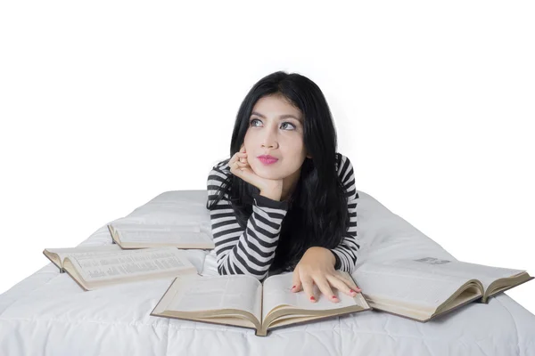 Lovely woman lying on bed with books — Stok fotoğraf