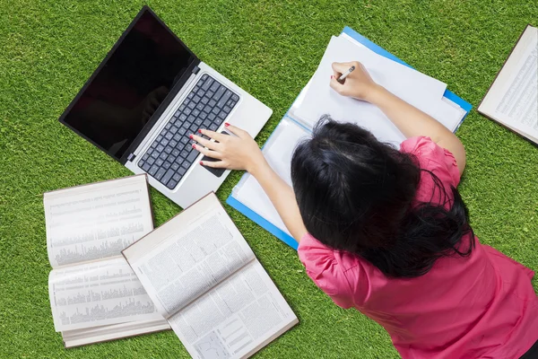 Estudiante universitario acostado en la hierba mientras estudia — Foto de Stock