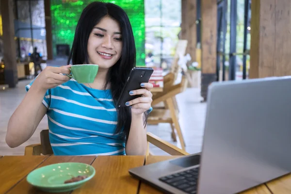 Mujer disfrutar del café, mientras que los mensajes de texto en el café — Foto de Stock