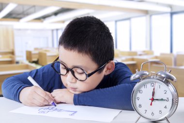 Sınıfta bir saatiyle masanın üzerinde çizim çocuk